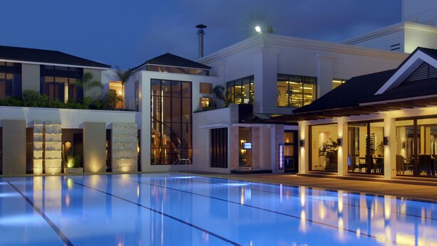 A modern hotel with a large outdoor swimming pool, a covered outdoor dining area, and a well-lit building facade. - Marco Polo Davao (Davao)