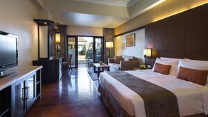 A hotel room with a large bed, a TV, a desk, and a seating area with chairs. - Marco Polo Davao (Davao)