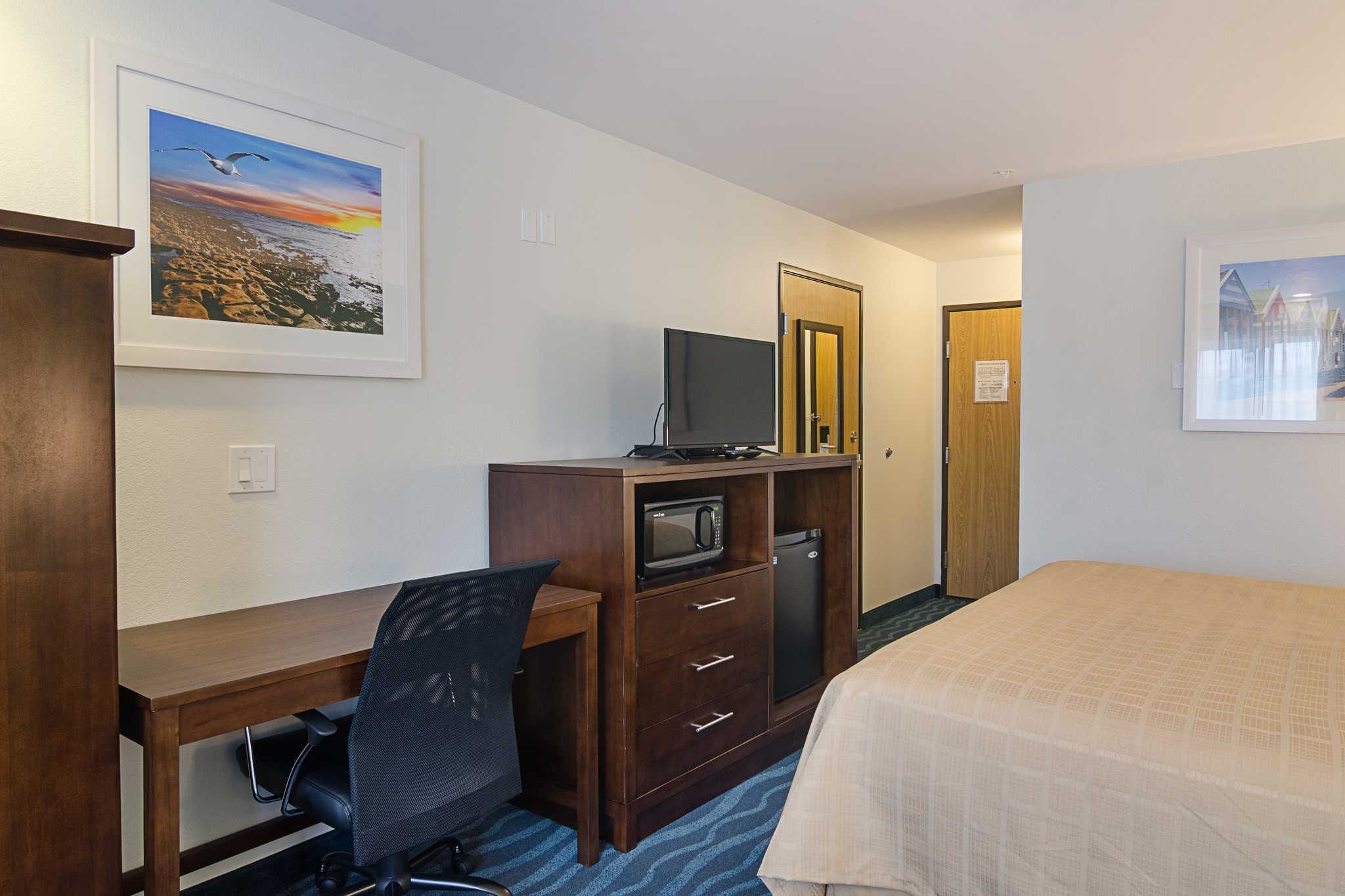 Habitación de hotel con escritorio, silla, cama y televisor.