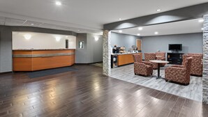 A modern hotel lobby with a reception desk, seating area, and a television. - Americas Best Value Inn & Suites Racine (Mount Pleasant)