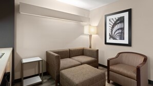 A hotel room with a sofa, a chair, a small table, and a framed picture on the wall. - Americas Best Value Inn & Suites Racine (Mount Pleasant)