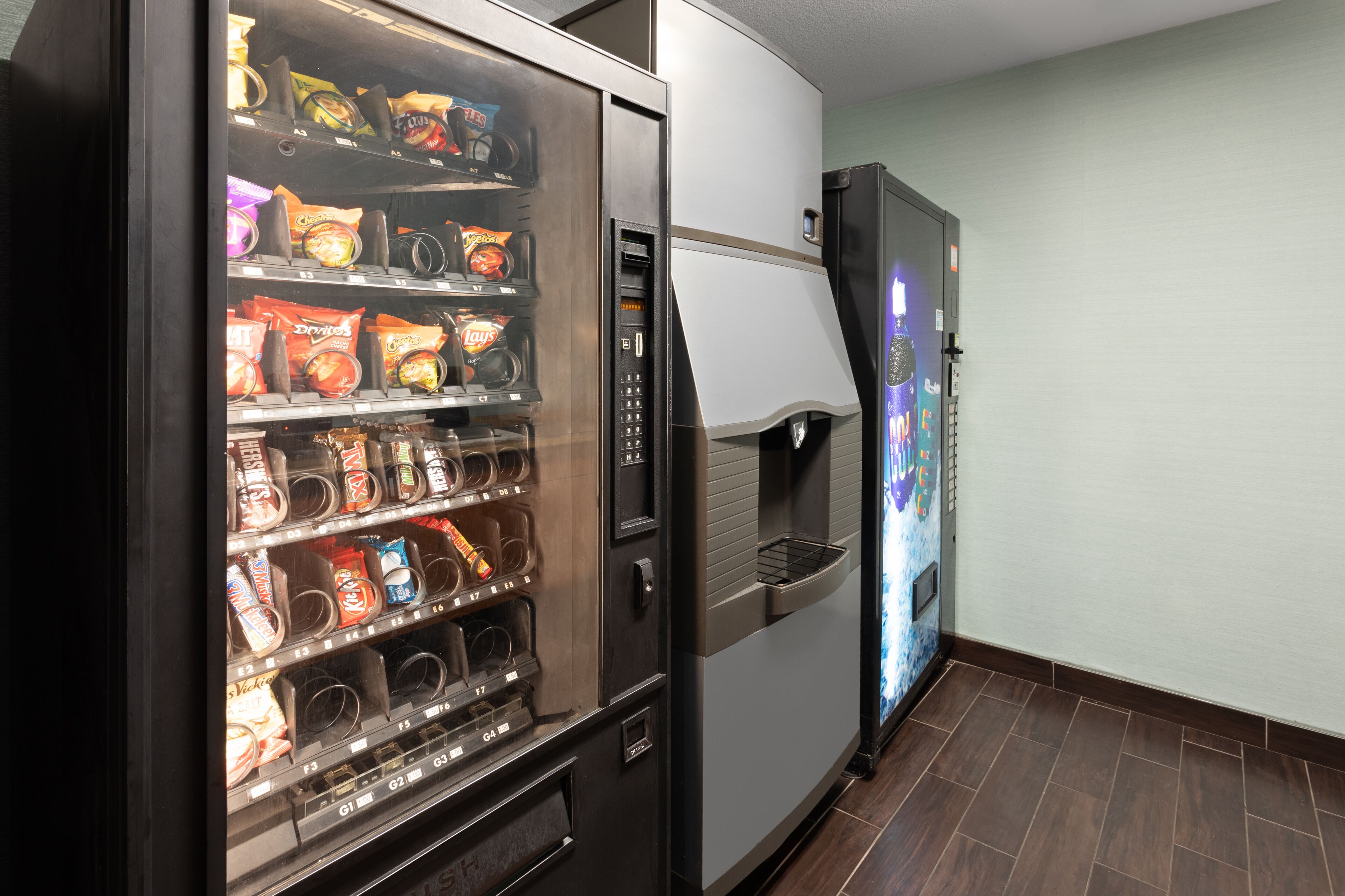 A vending machine stocked with snacks and a refrigerator.