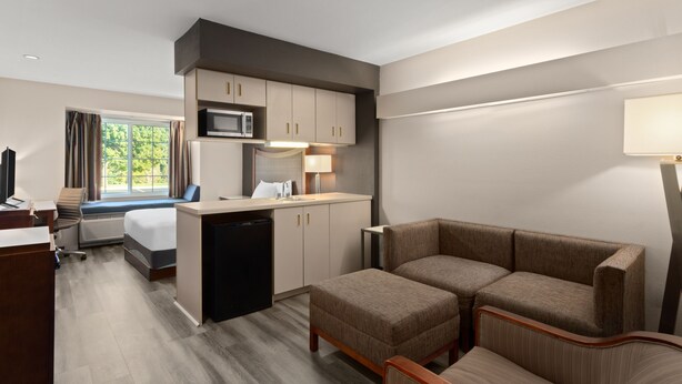 A hotel room with a kitchenette, a sofa, a desk, a TV, and a window with curtains. - Americas Best Value Inn & Suites Racine (Mount Pleasant)
