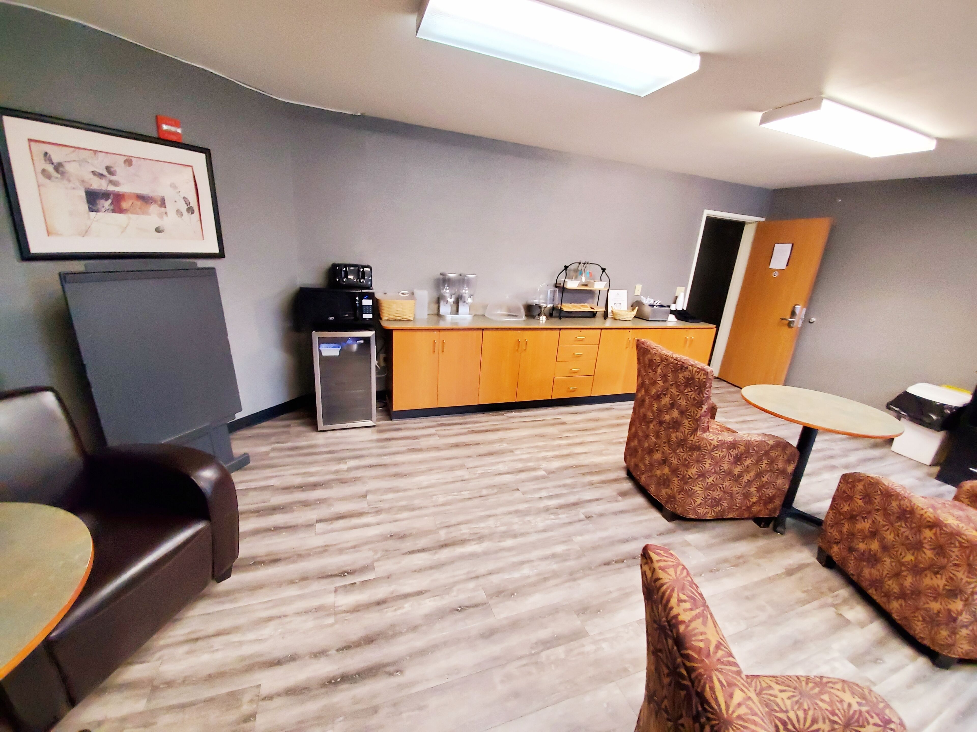 Habitación de hotel con kitchenette, un sofá, un sillón estampado y una mesita.