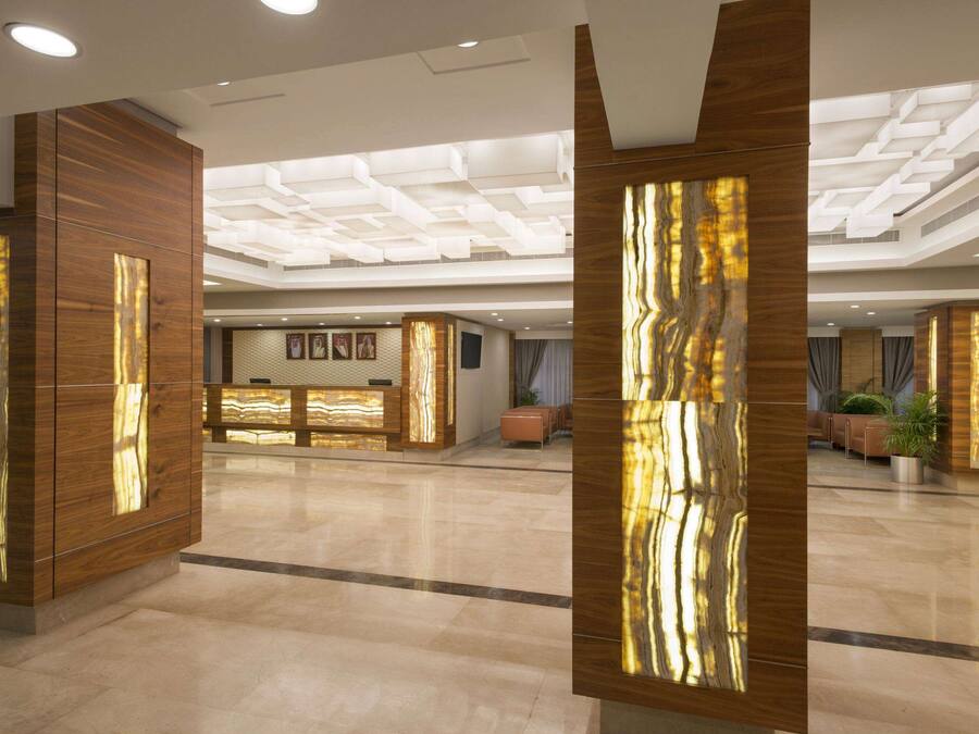 Un vestíbulo amplio con una recepción, paneles de madera y un diseño de techo moderno.
