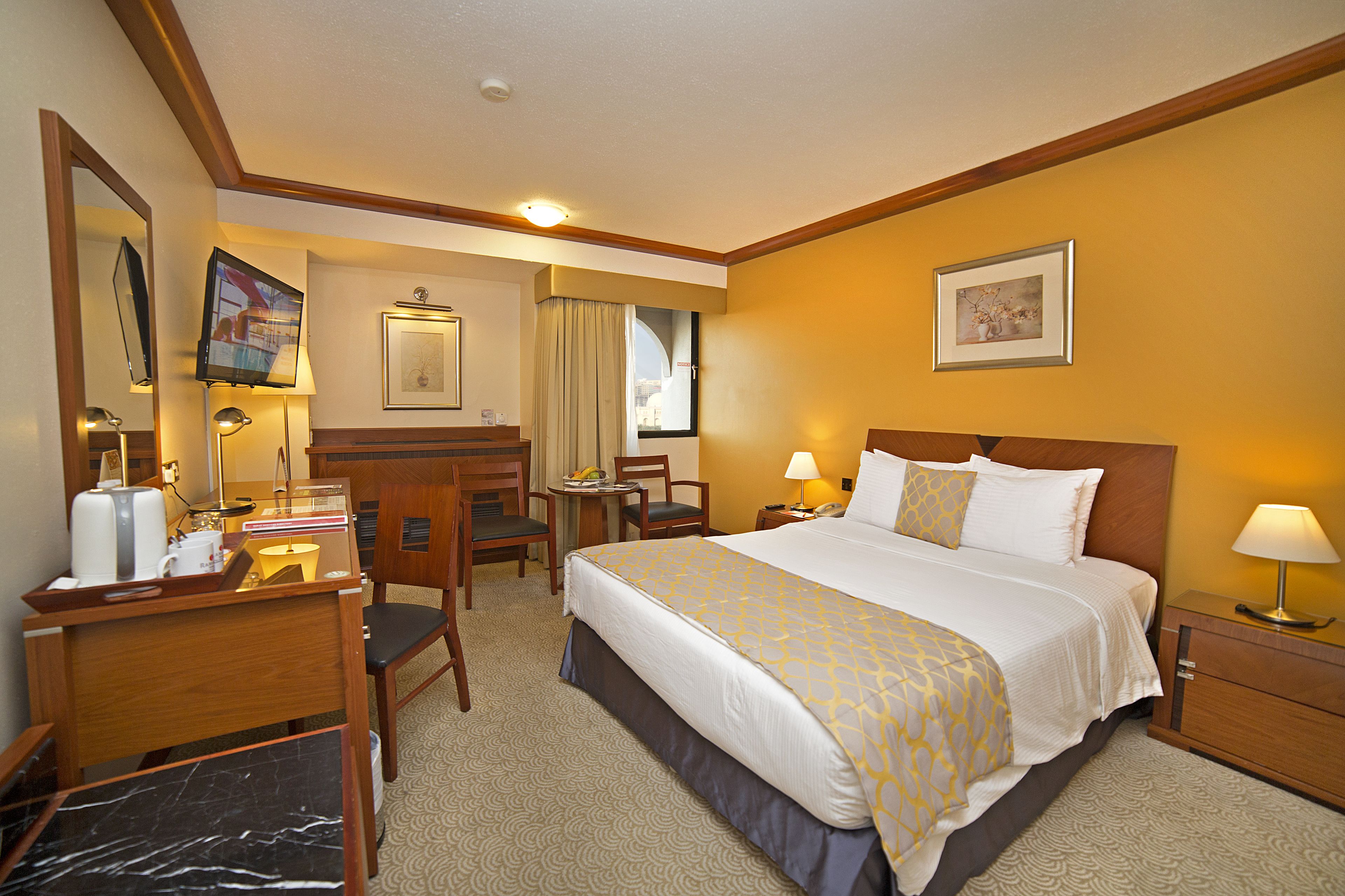 Ein Hotelzimmer mit Bett, Schreibtisch, Stuhl und Fernseher.