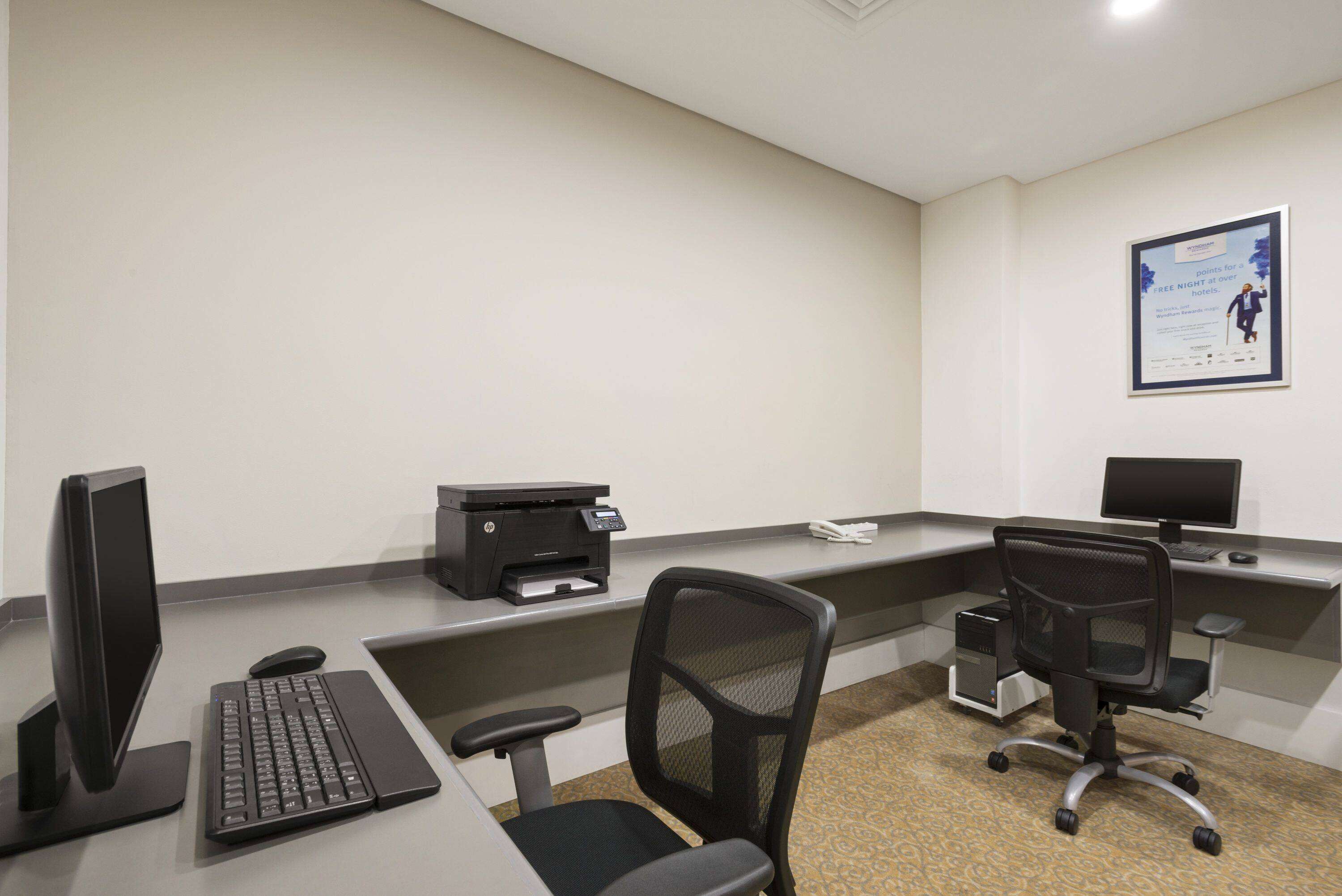Un espacio de oficina moderno con una computadora de escritorio, una impresora y una silla de oficina negra.