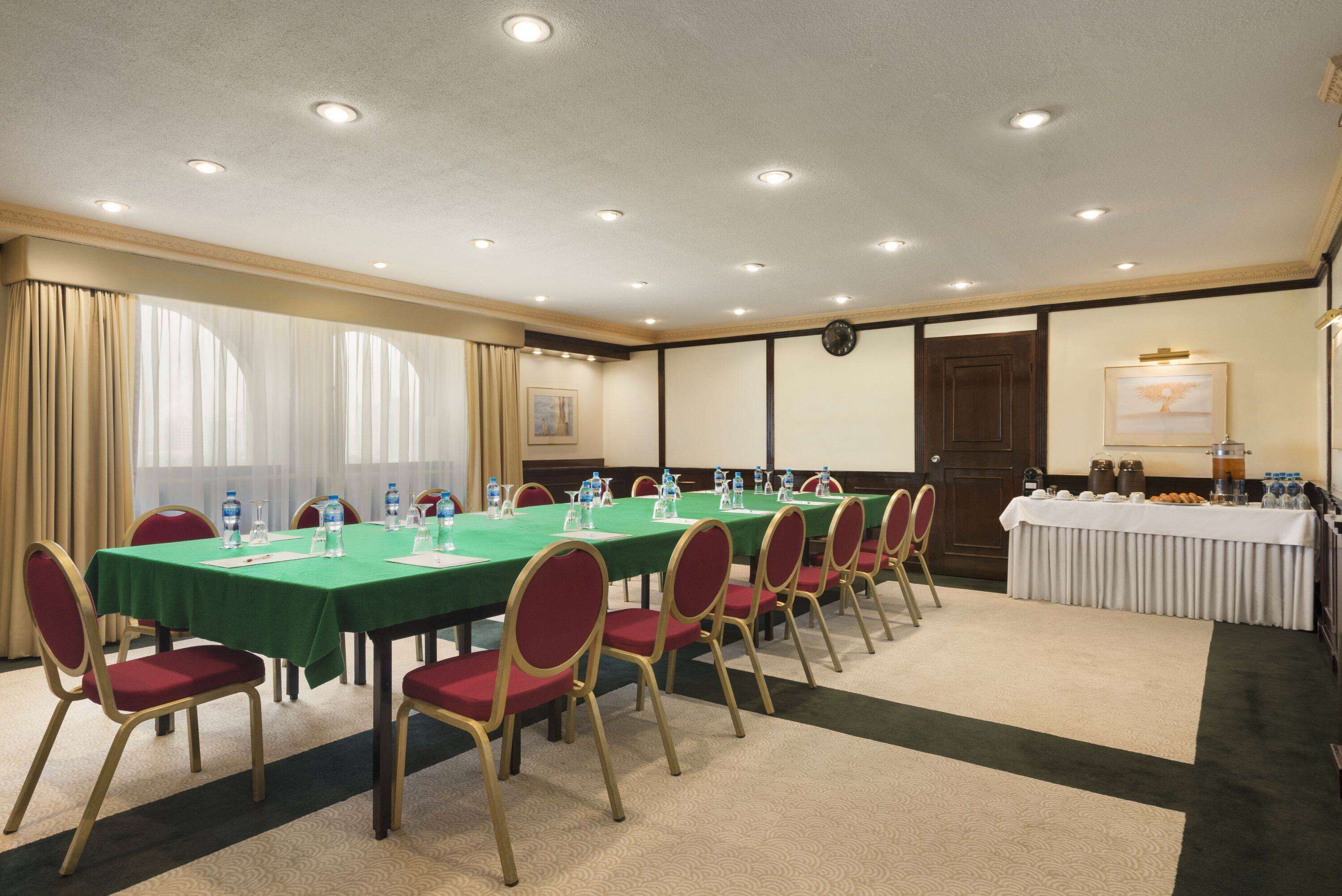 A conference room with a long table, red chairs, and a white tablecloth.