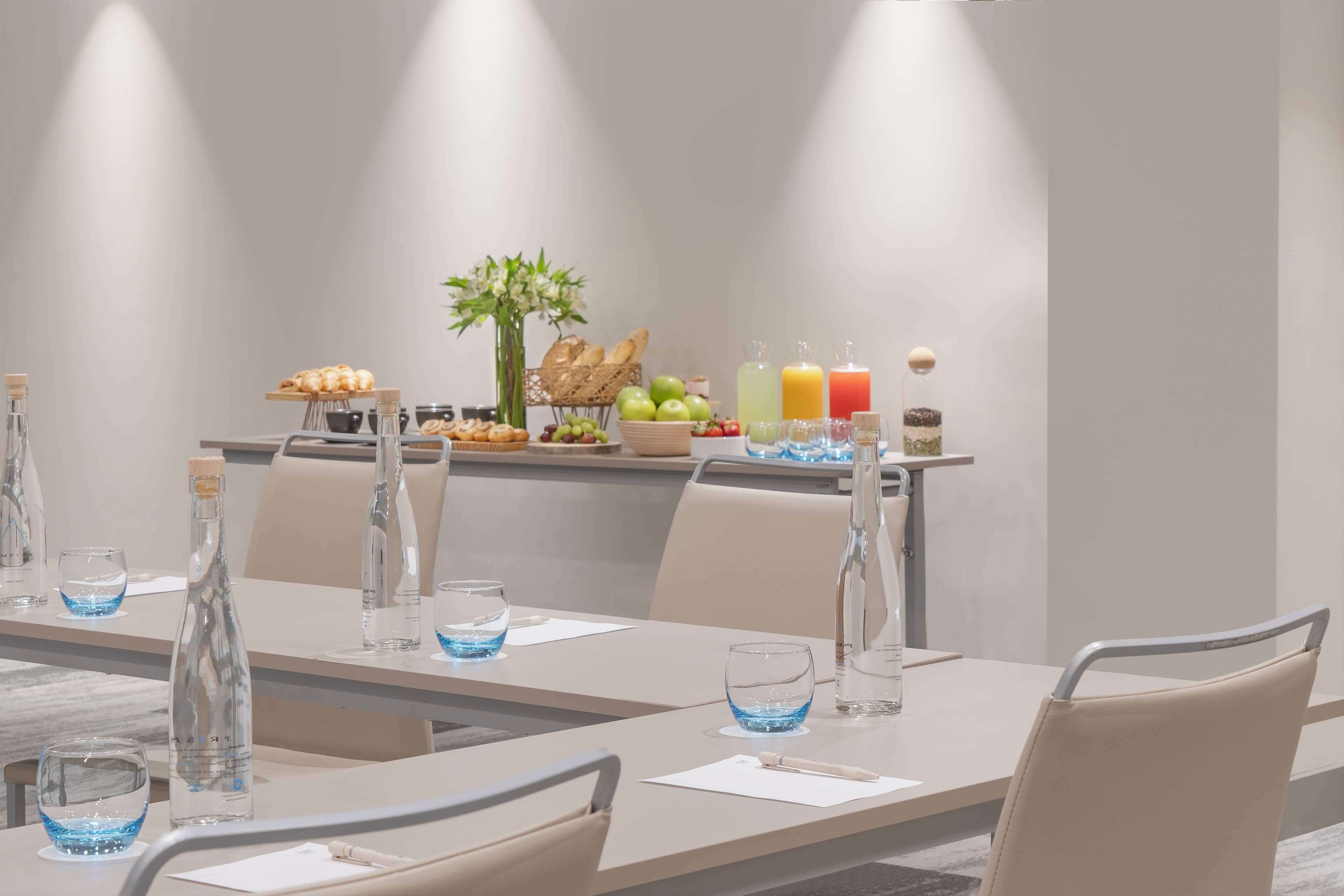 Een vergaderruimte met een lange tafel, stoelen en een buffet met eten en drinken.