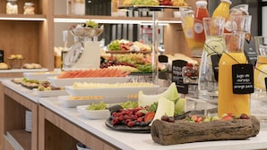 Un buffet proposant une variété de fruits, de fromages et de jus de fruits.