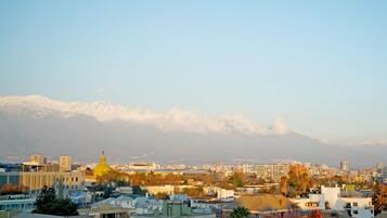 A cityscape with a prominent yellow dome, residential buildings, and snow-capped mountains in the background.