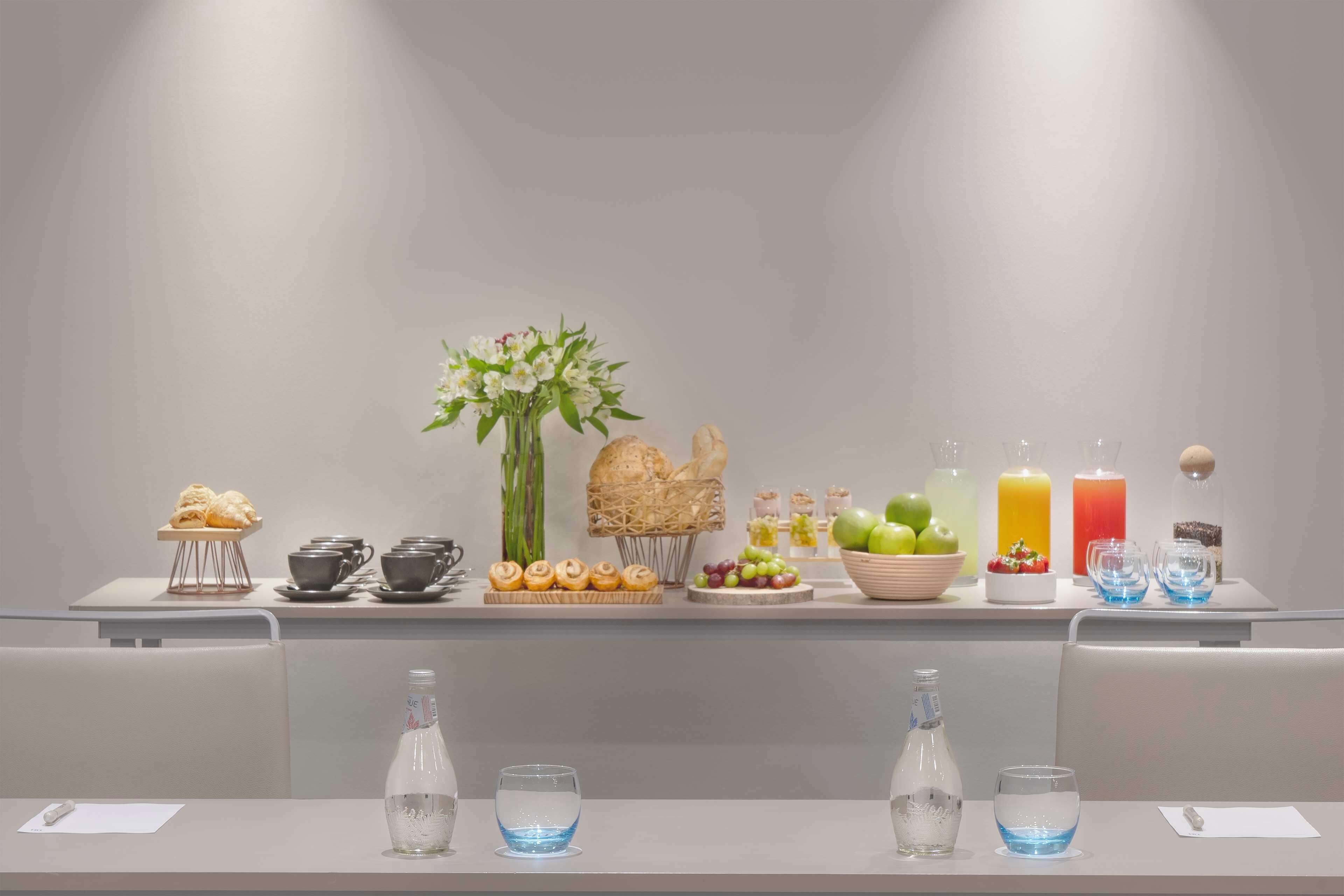 A neatly arranged buffet table with pastries, fruits, and beverages.