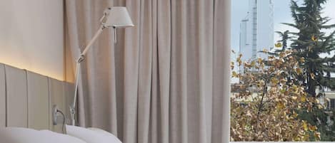 Habitación de hotel con cama, lámpara de noche, un florero con flores y un libro sobre la cama.