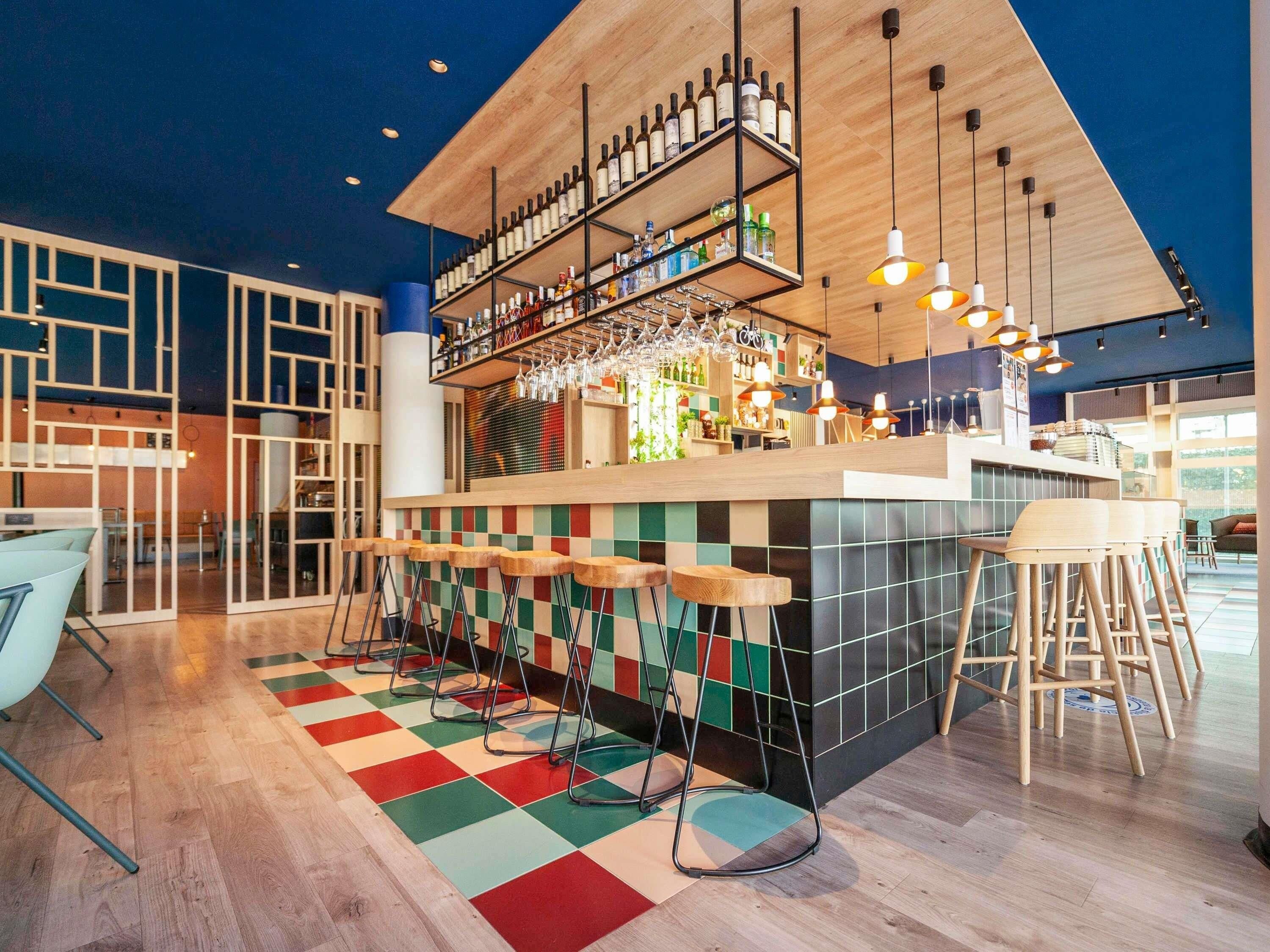 Un espace bar avec un sol à carreaux, des tabourets de bar et des étagères remplies de bouteilles.