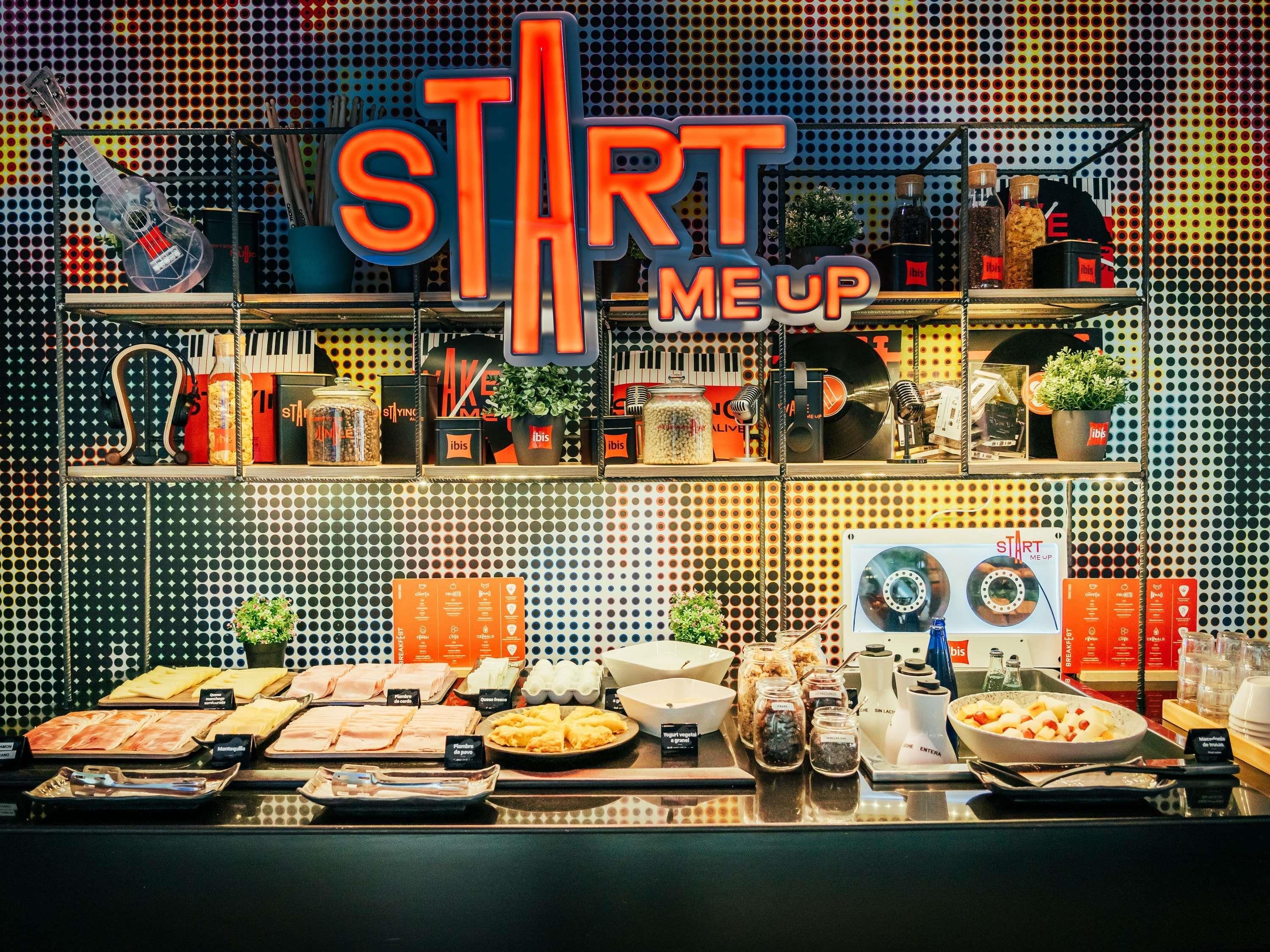 Un bufé de desayuno con diversas opciones de comida y un cartel que dice 'START ME UP'.