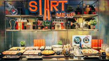 Un bufé de desayuno con diversas opciones de comida y un cartel que dice 'START ME UP'.