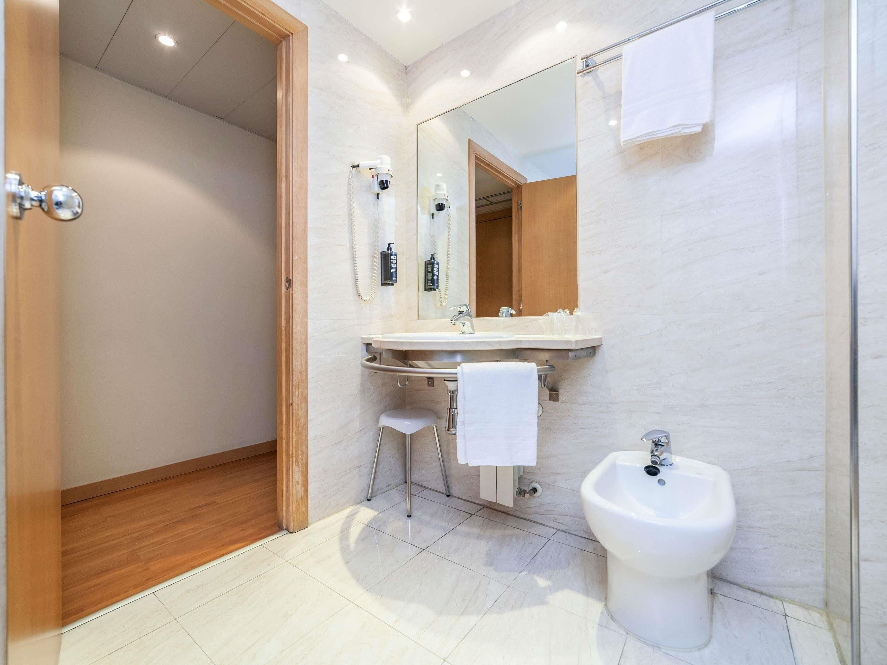 A modern bathroom with a shower, sink, and bidet.