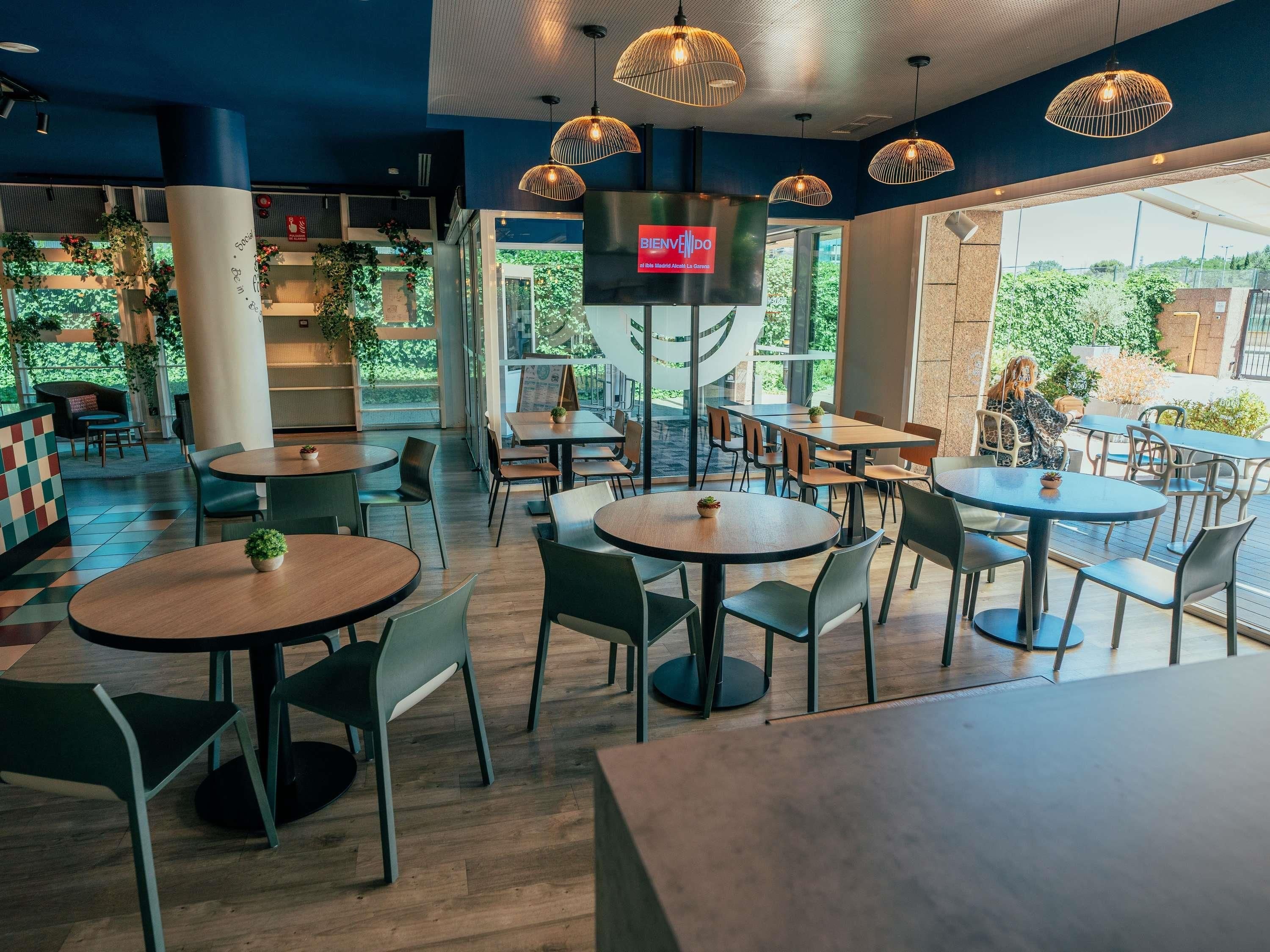 A modern cafe interior with round tables, chairs, and hanging pendant lights.