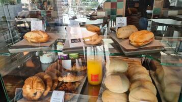 Una vitrina de panadería con diversos productos horneados, como cruasanes, sándwiches y panecillos.