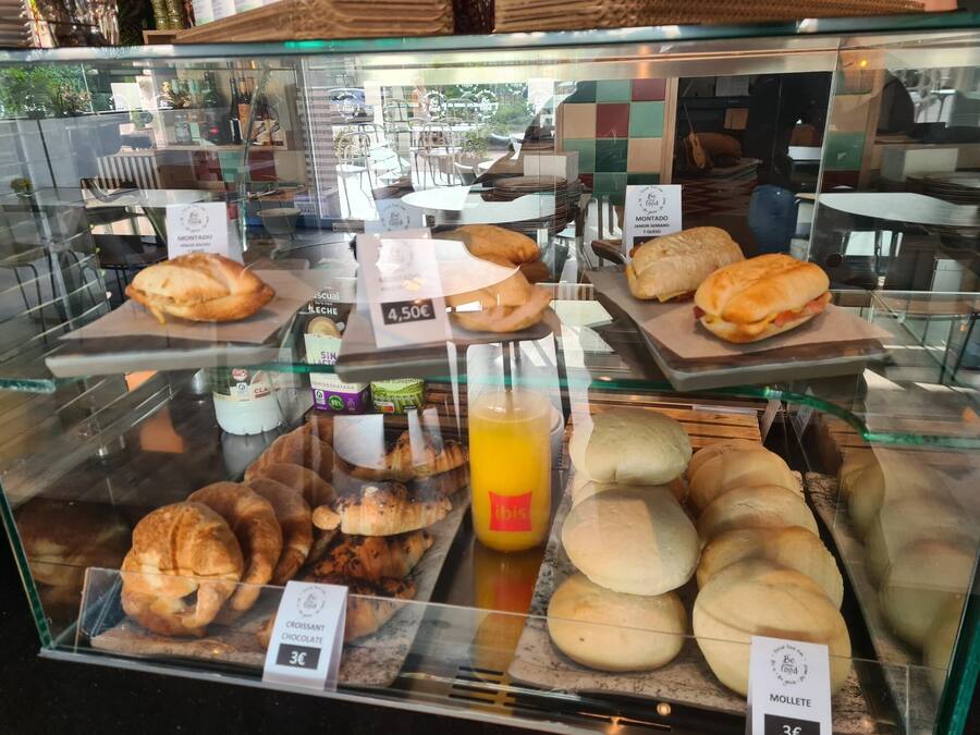 Una vitrina de panadería con diversos productos horneados, como cruasanes, sándwiches y panecillos.