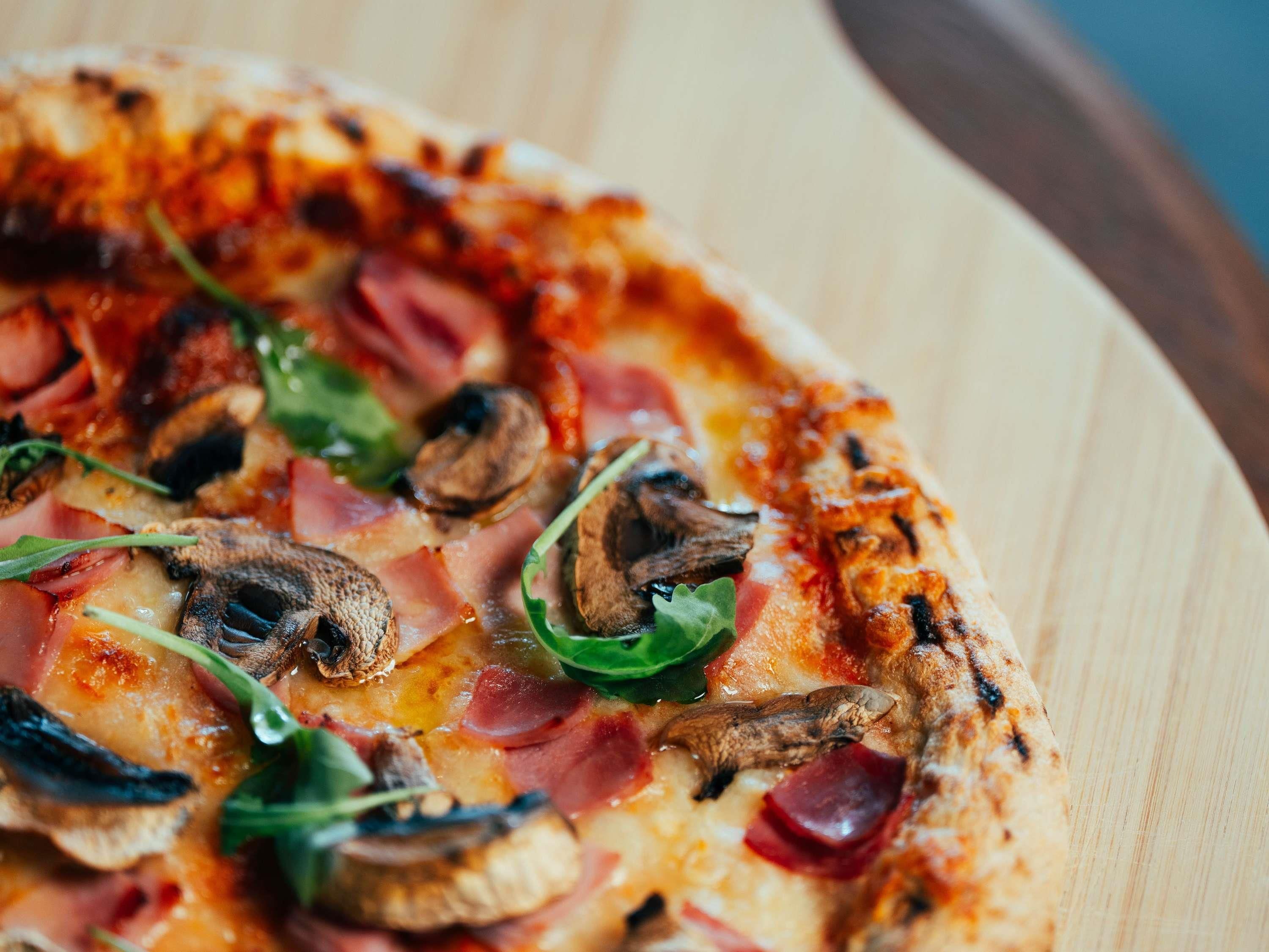 Eine Pizza mit verschiedenen Belägen auf einem Holzboden.
