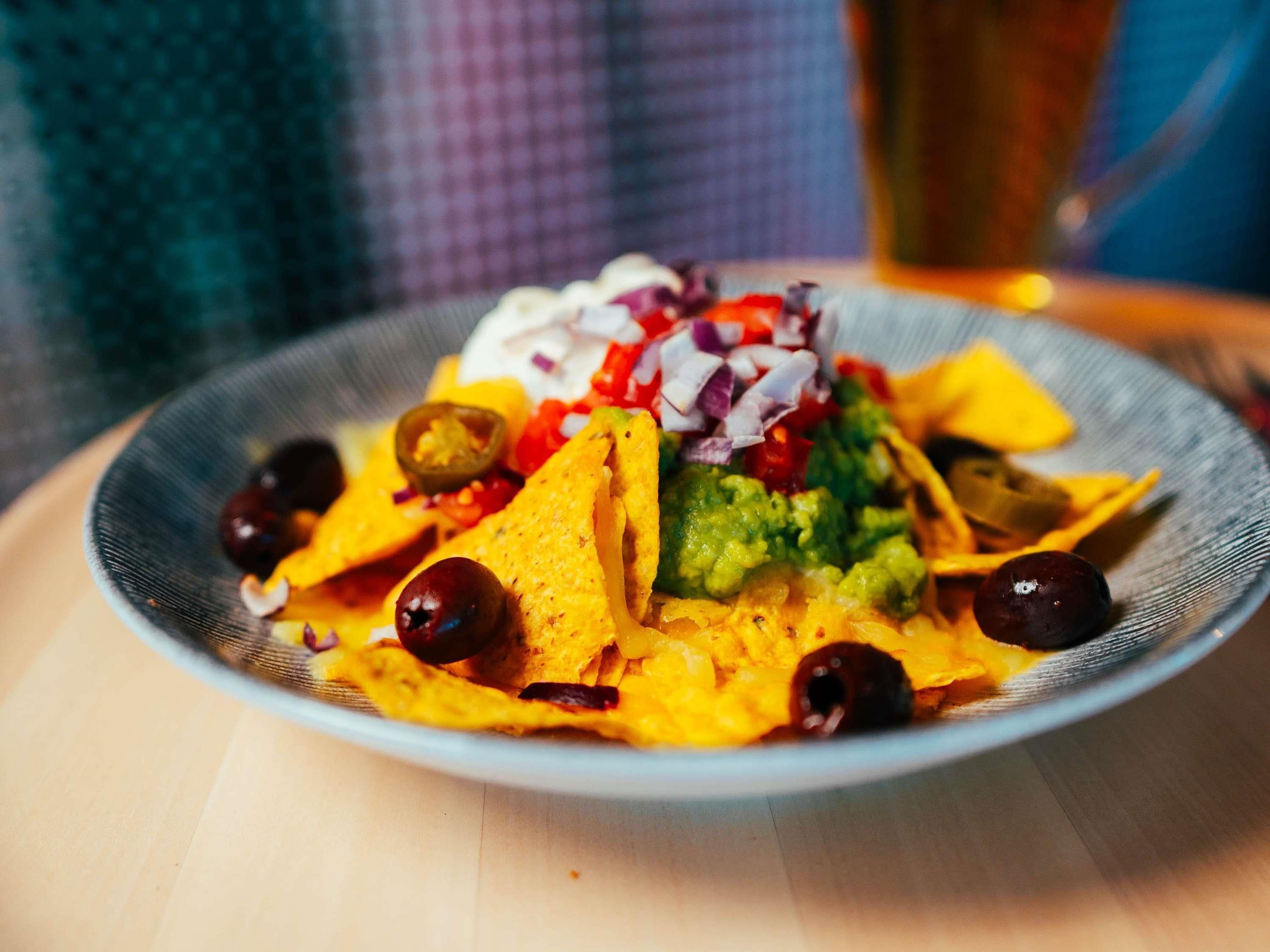 Eine Portion Nachos mit Guacamole, roten Zwiebeln, Jalapeños und Oliven.