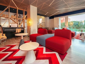 Un área de descanso moderna con un piano, asientos y vistas al exterior.