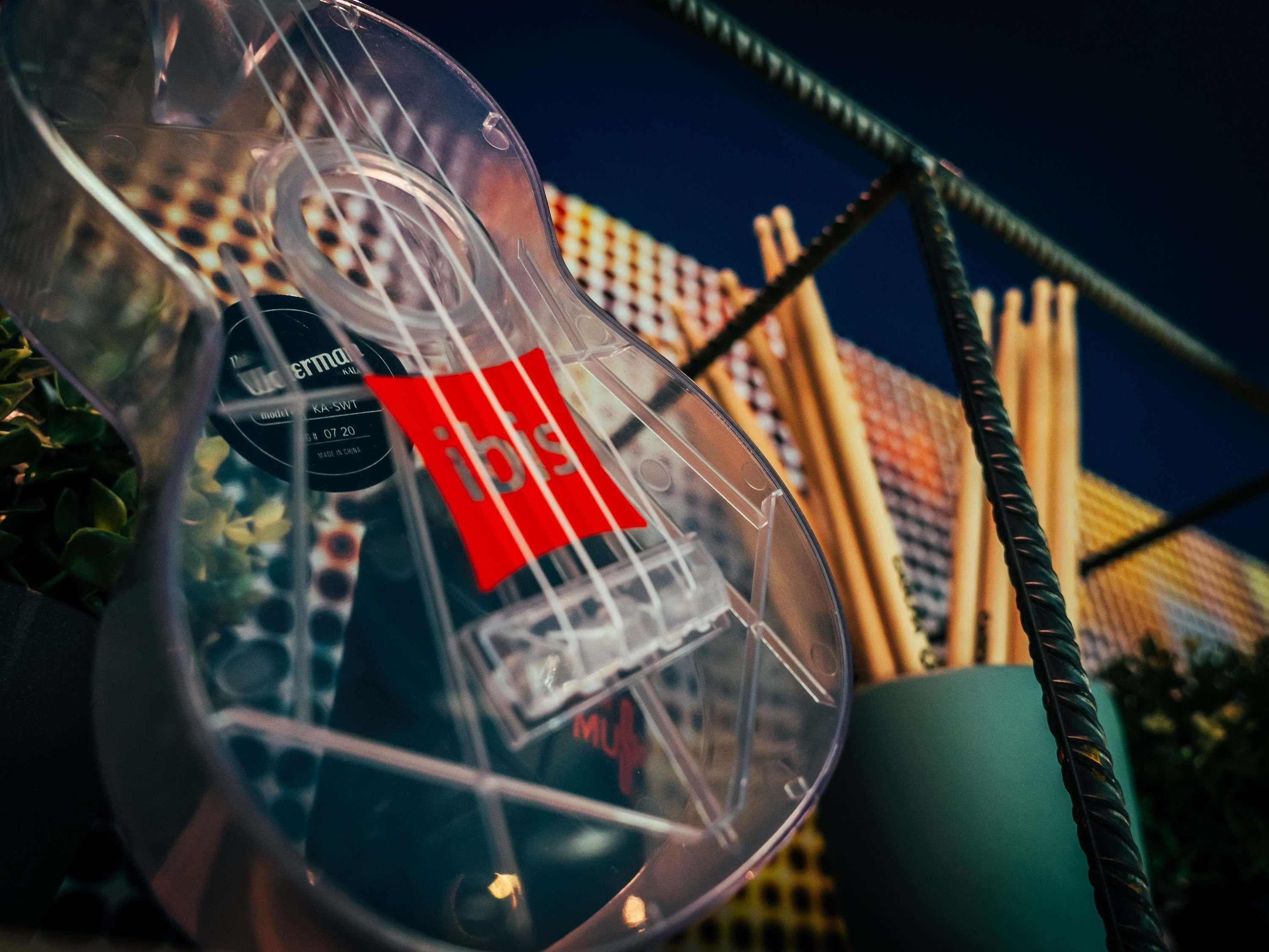 A clear view of a glass object with a red label, possibly a bottle, with a background of a building with a checkered pattern.