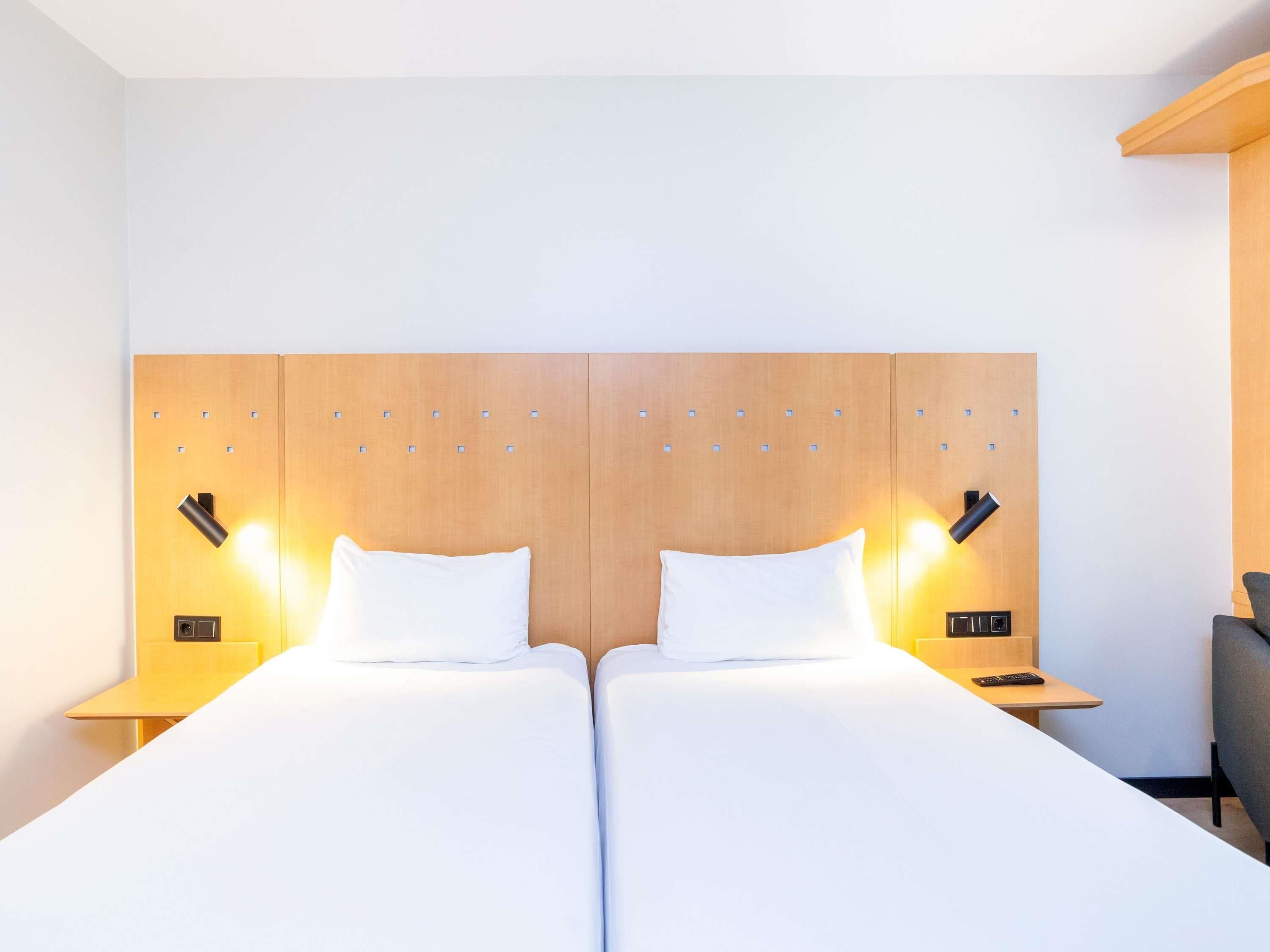 A hotel room with a double bed, two bedside tables, and a wooden headboard.