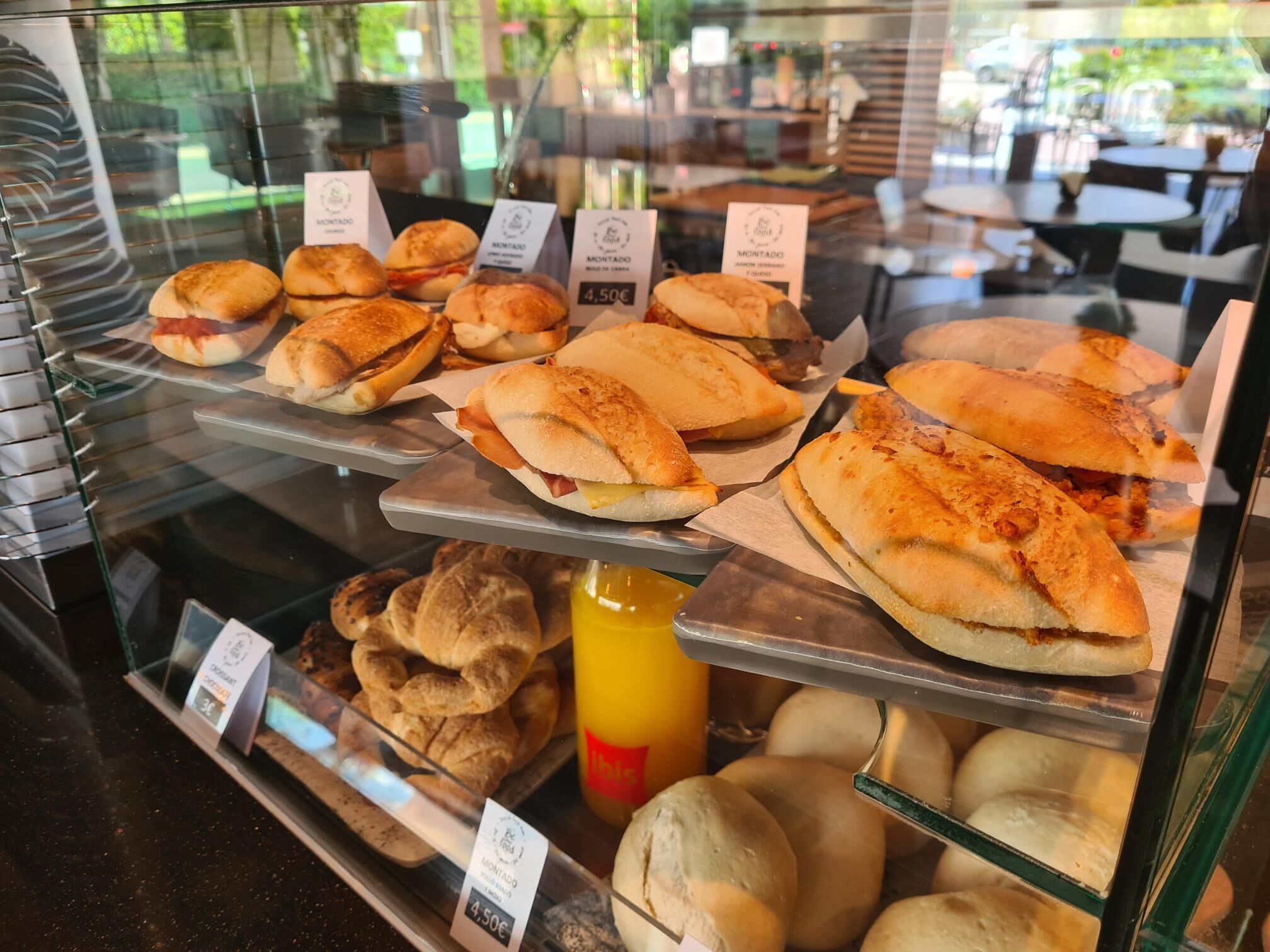 Ett bageridisplay med olika sorters bröd och bakverk, inklusive smörgåsar och frallor, till priset av 4,50 euro.