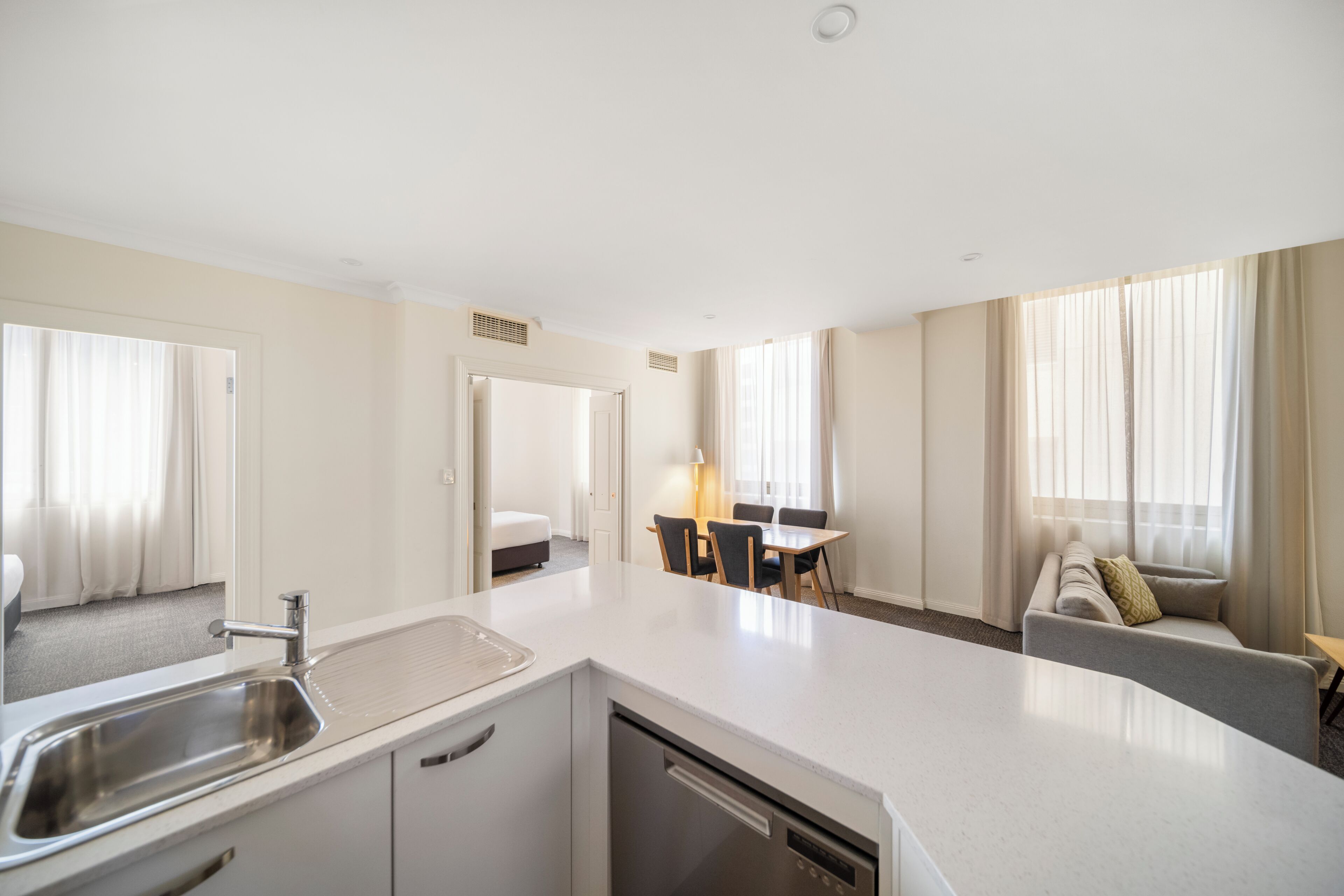 Habitación de hotel con kitchenette, zona de comedor, sofá y ventana con cortinas.