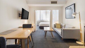 A hotel room with a bed, a sofa, a desk, a TV, and a framed picture on the wall. - Mantra Adelaide Central (Adelaide)