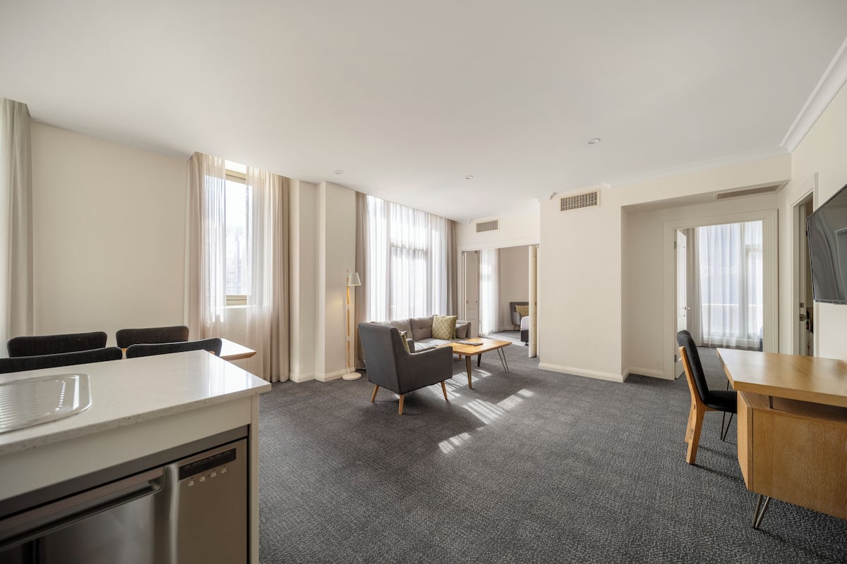 Een hotelkamer met een zithoek, een bank, een televisie en een bureau.