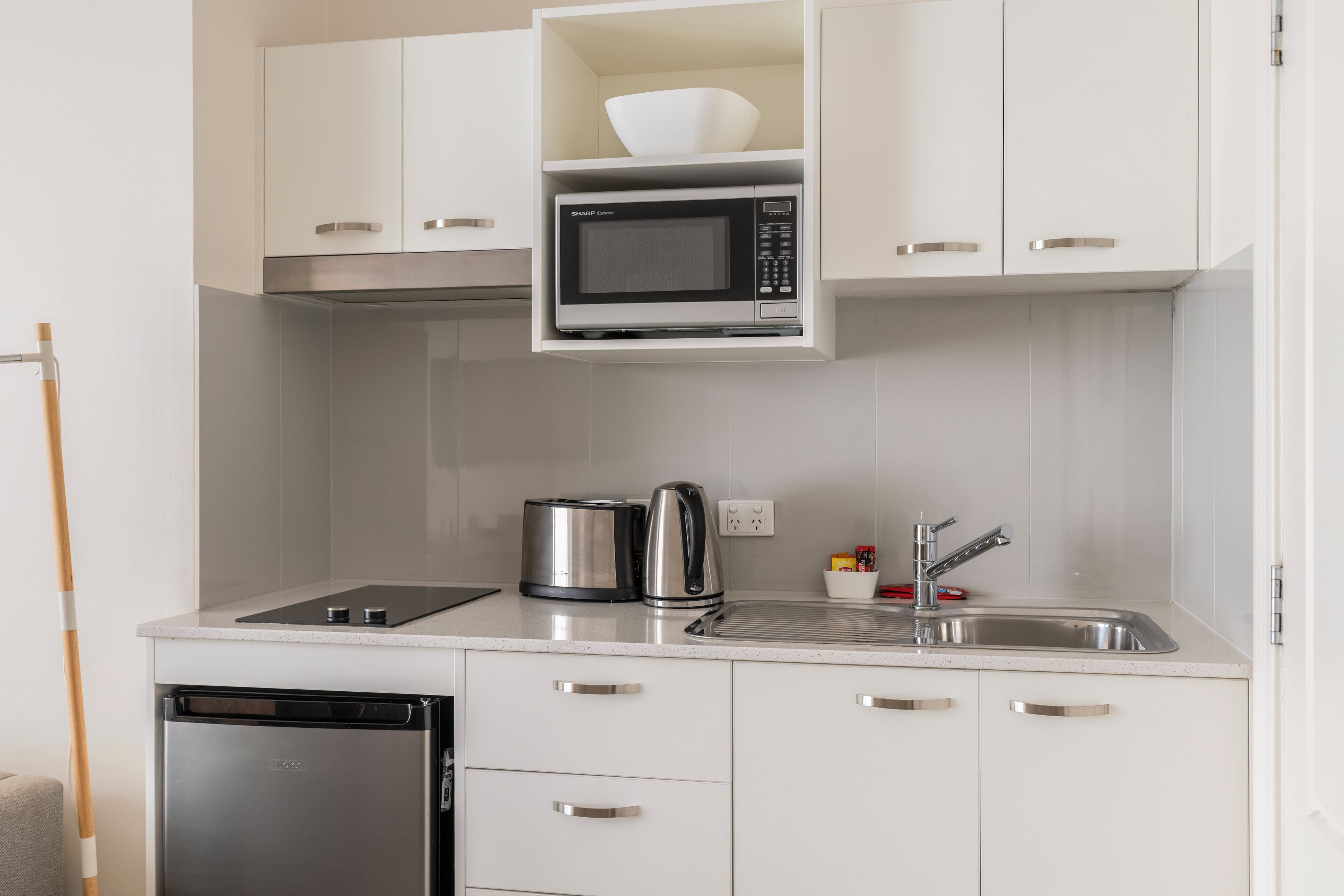 A compact kitchen with a microwave, toaster, kettle, and dishwasher.