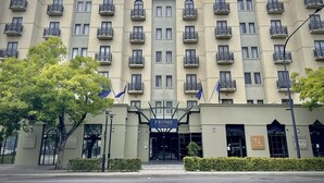 Un edificio de varios pisos con balcones, un letrero que dice "EPOME apartments" y banderas.