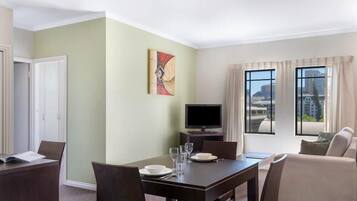 A hotel room with a dining area, a TV, and a view of the city.