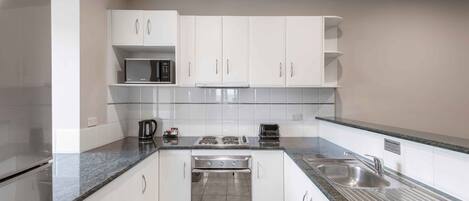 A modern kitchen with white cabinets, stainless steel appliances, and granite countertops.
