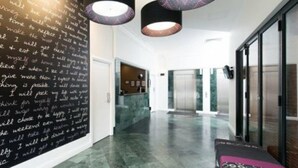 Un amplio vestíbulo con suelo de mármol, un sofá negro y una pared llena de notas escritas a mano.