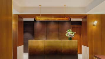 A reception area with a modern design, featuring a wooden reception desk, a patterned floor, and a wall-mounted light fixture.