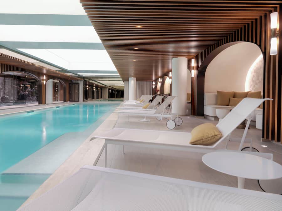 A modern indoor pool area with lounge chairs and a seating area.