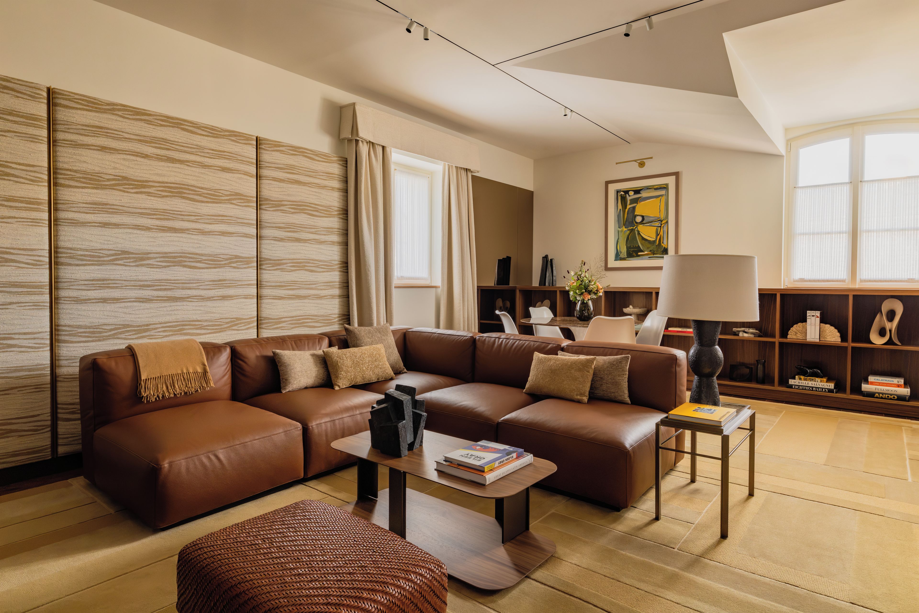 A modern living room with a sectional sofa, a coffee table, and a bookshelf.
