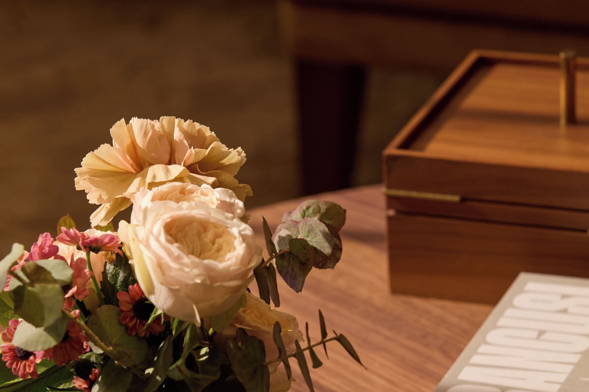 A wooden table with a vase of flowers and a book titled "BRANQUIS".