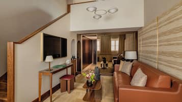 Ein modernes Wohnzimmer mit einem braunen Ledersofa, einem Holztisch, einem an der Wand befestigten Fernseher und einer Treppe zu einer oberen Ebene.