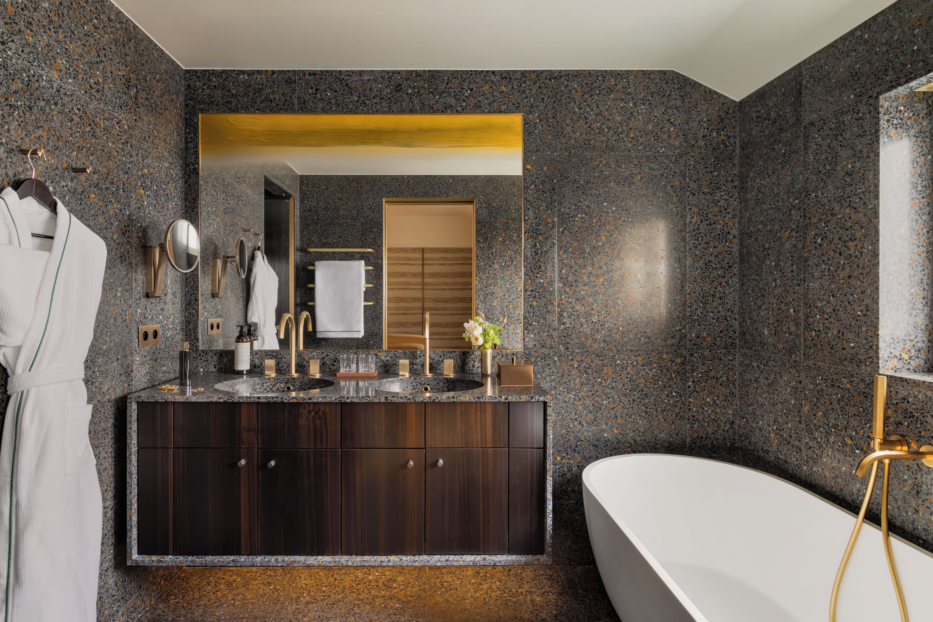 A modern bathroom with a freestanding bathtub, dark wood vanity, and a large mirror.