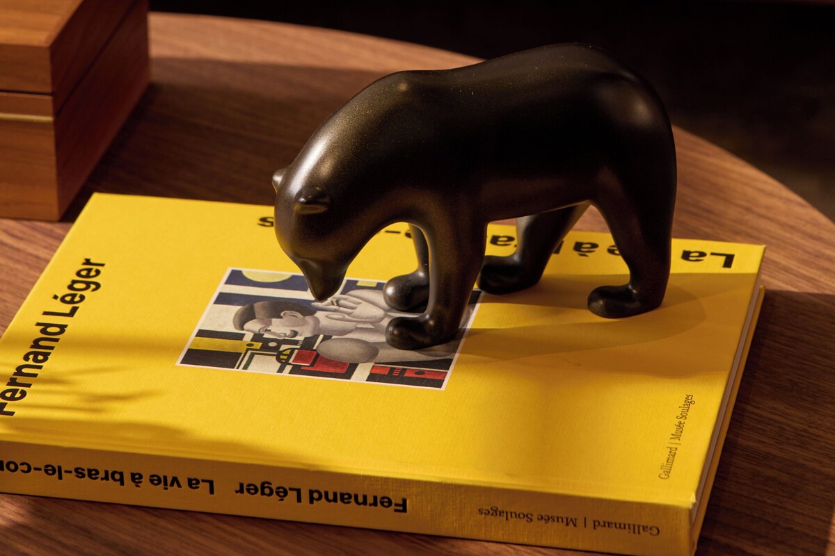 A book titled "Fernand LÃ©ger" on a wooden table with a bear figurine on top.