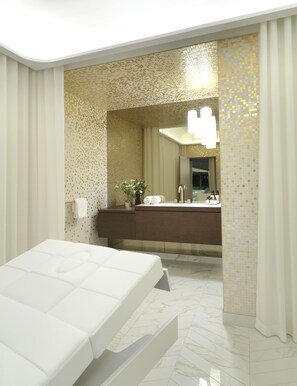 A hotel room with a bed, a bathroom with a mirror, and a shower area.