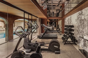 Un gimnasio con cintas de correr, elípticas y máquinas de pesas.