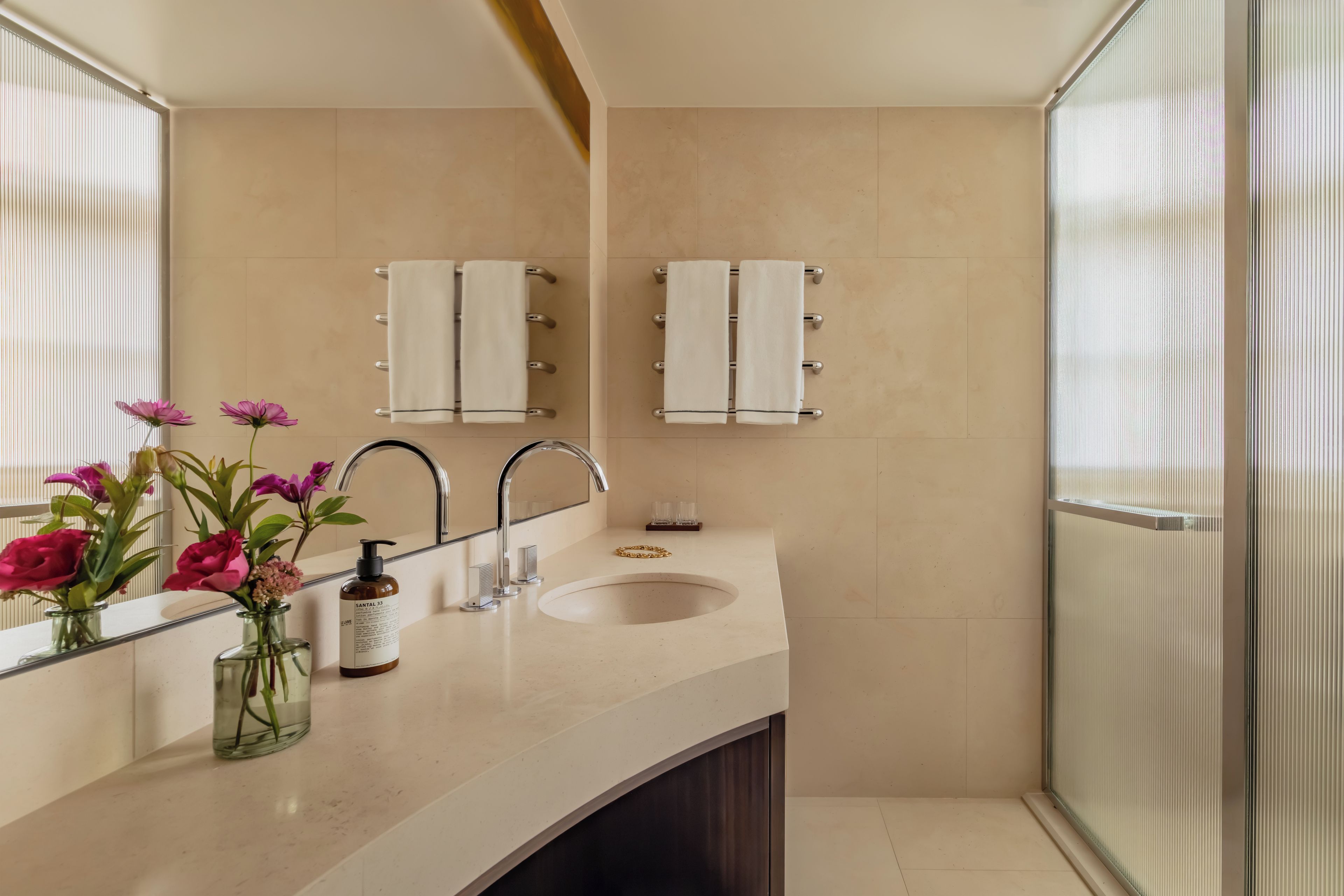 A bathroom with a large mirror, two sinks, and a glass shower enclosure.