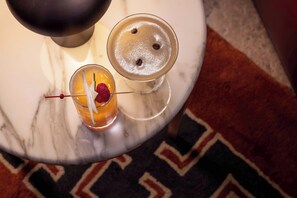 Two cocktails on a marble table with a patterned rug in the background. - Hotel d'Aubusson (Paris)