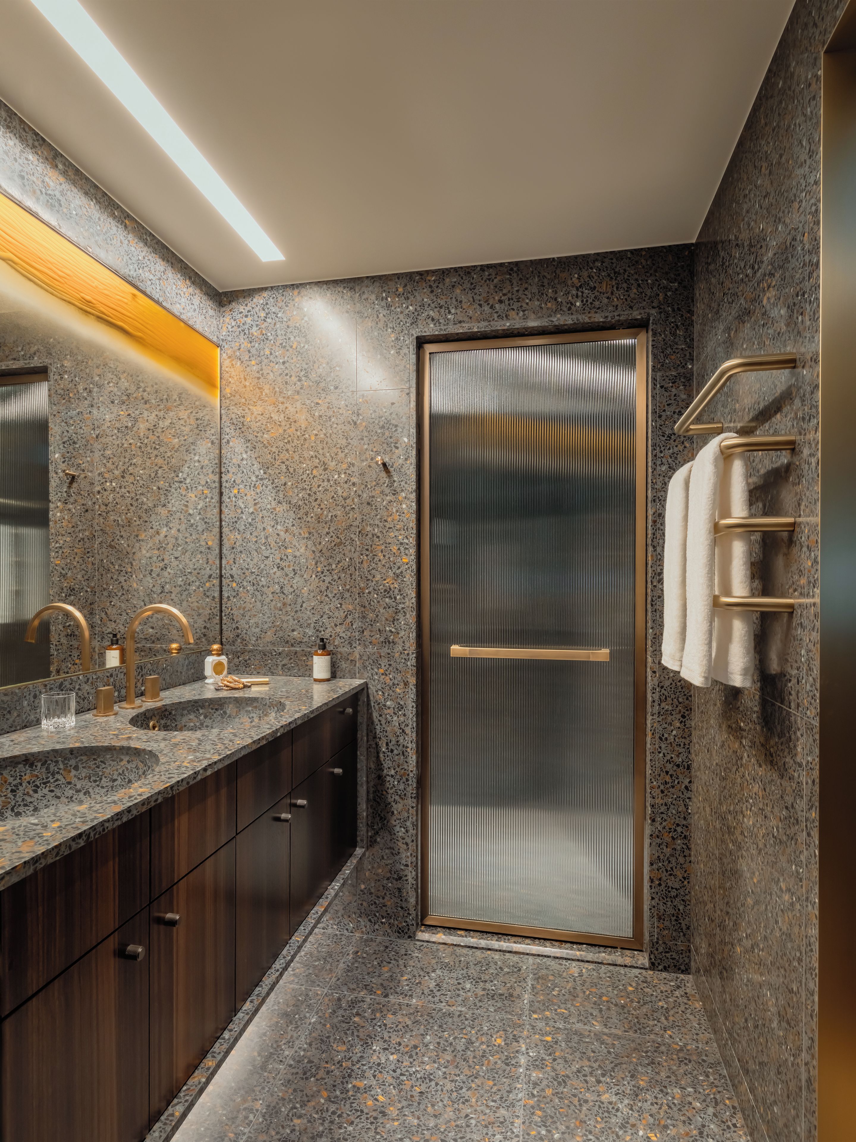 Une salle de bain moderne avec des comptoirs en granit, une douche en verre et un porte-serviettes.